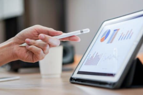 auditorías retributivas Mano sosteniendo un lápiz señalando gráficos de la auditoría retributiva en una tablet sobre una mesa.
